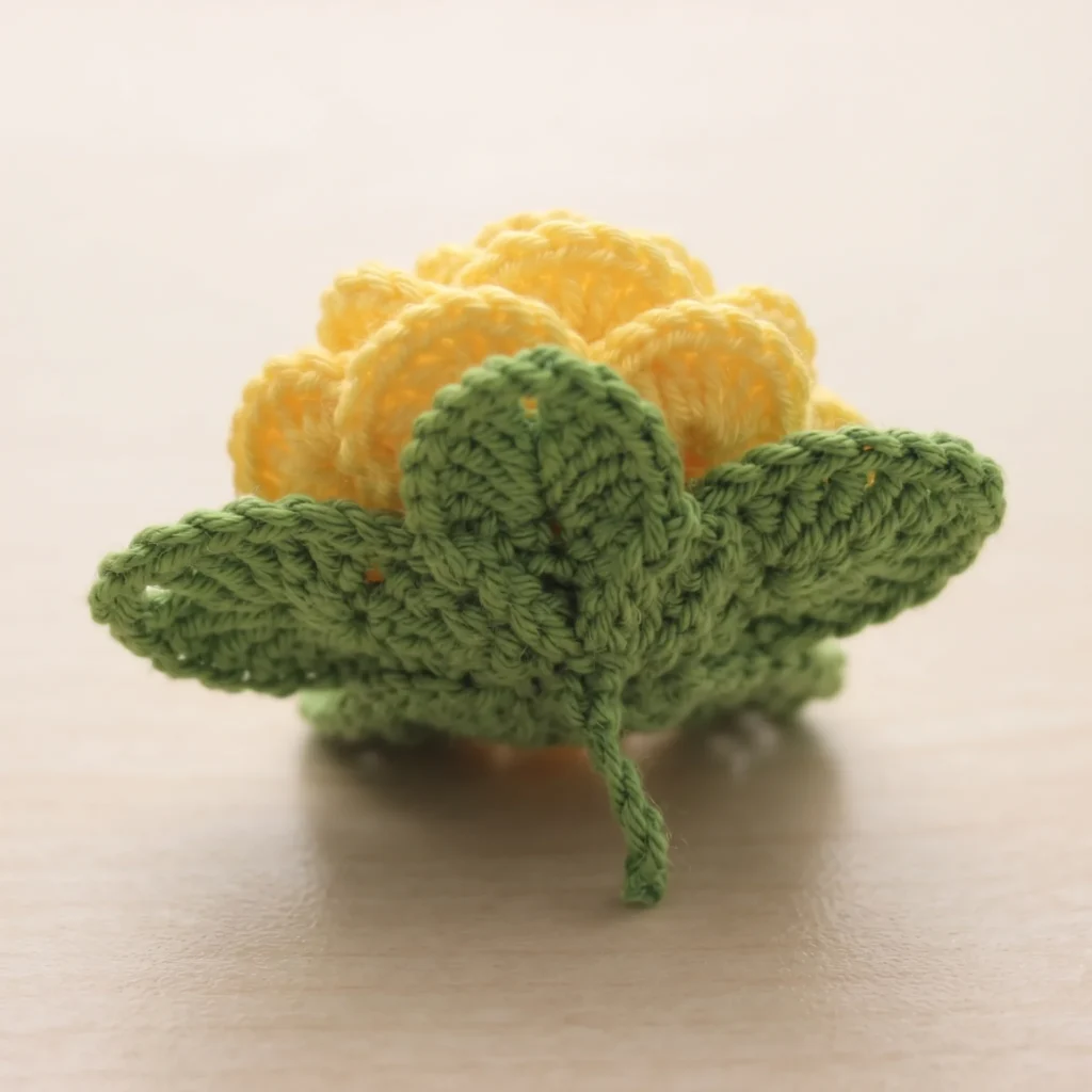 Finished 3d crochet rose with sepal and leaves attached, side view
