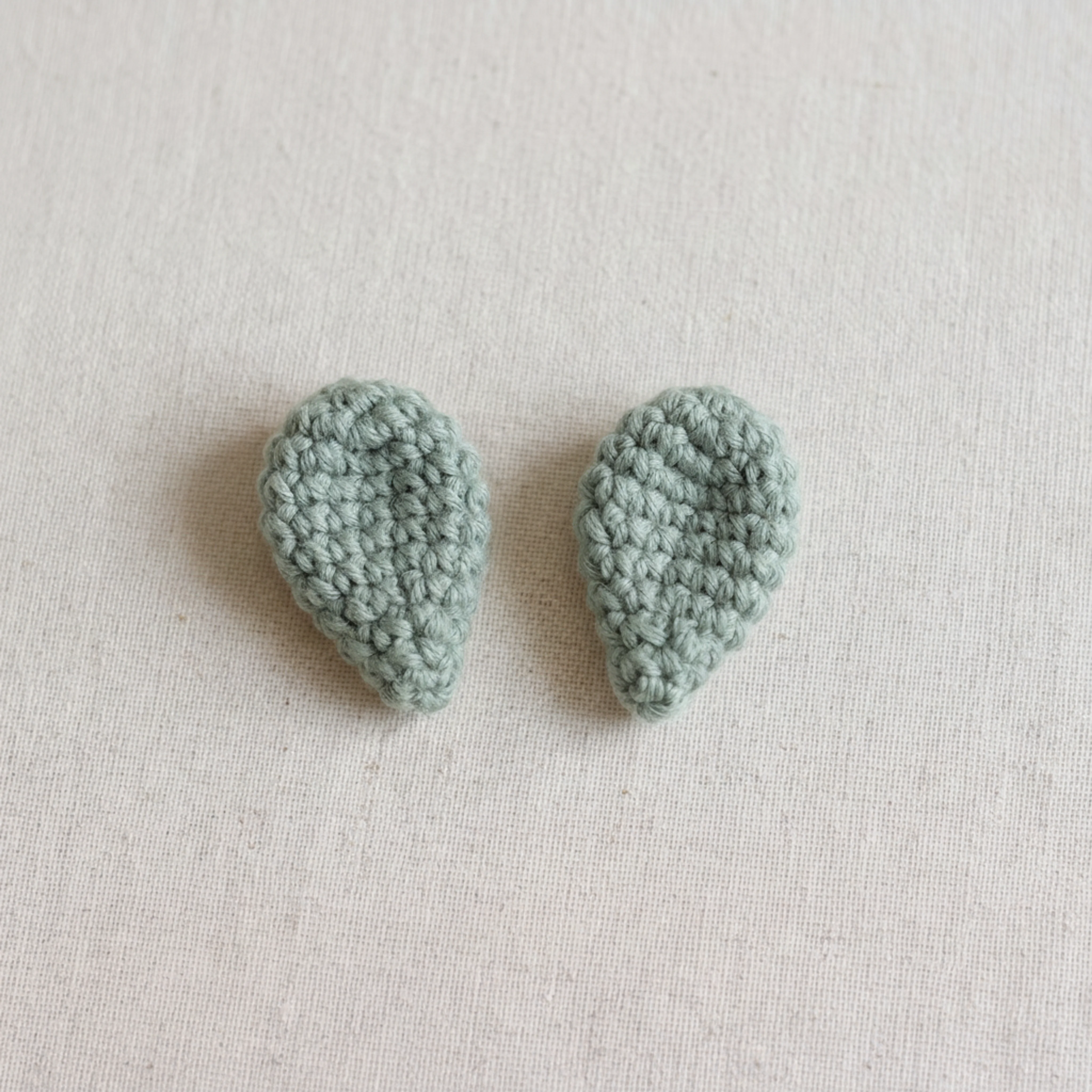 Two crocheted ears laid flat, ready to be sewn onto the crochet lamb keychain