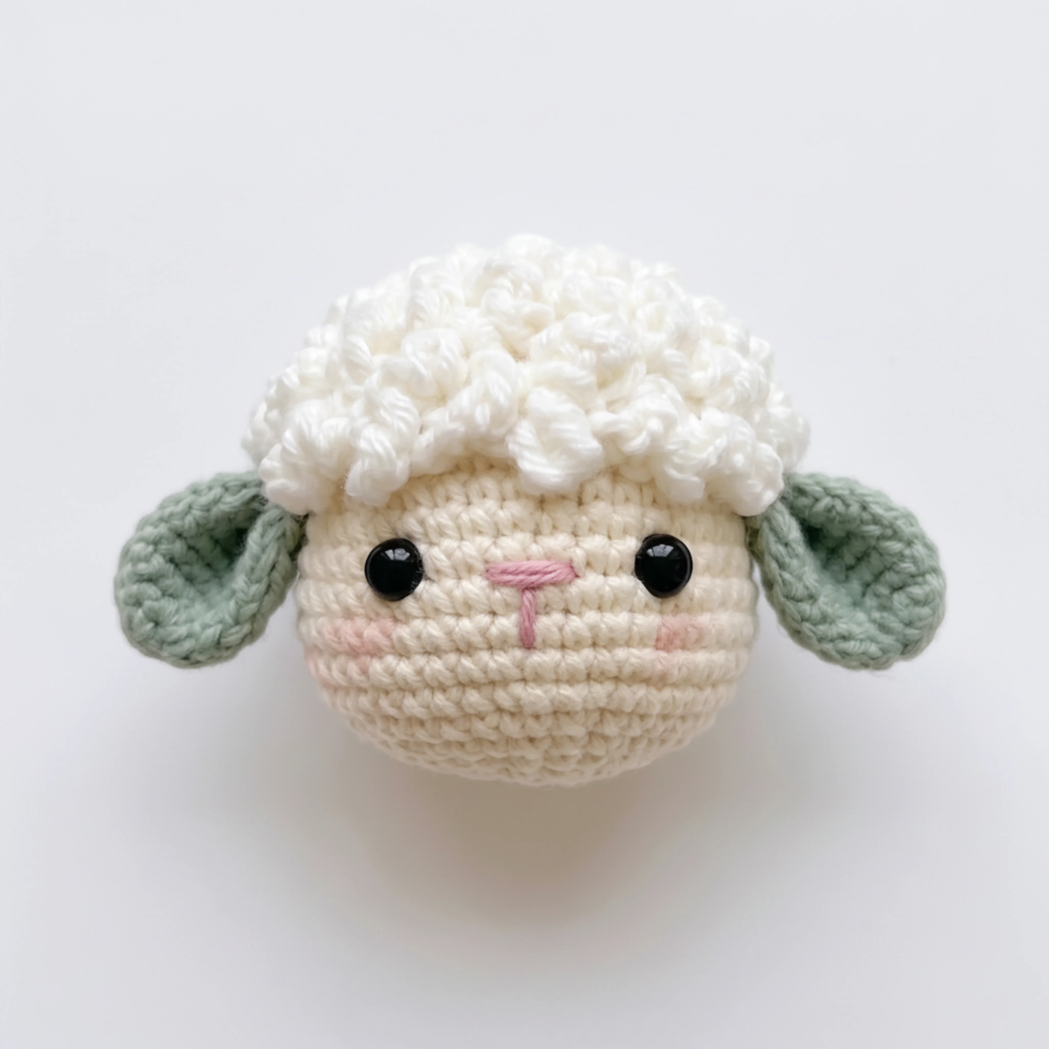 The finished head of the crochet lamb keychain with wool cap and ears attached