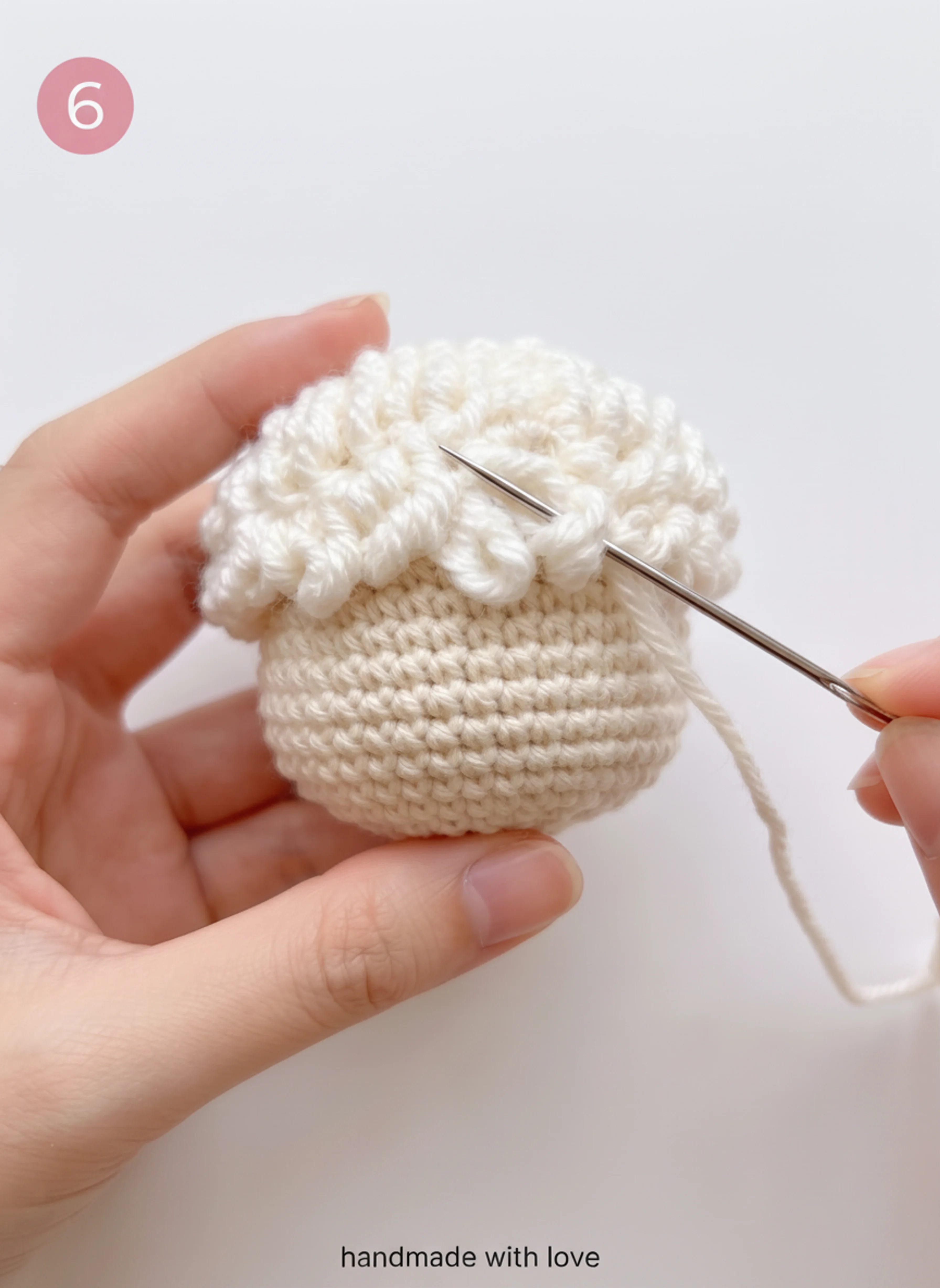 Sewing the wool cap onto the head of the crochet lamb keychain