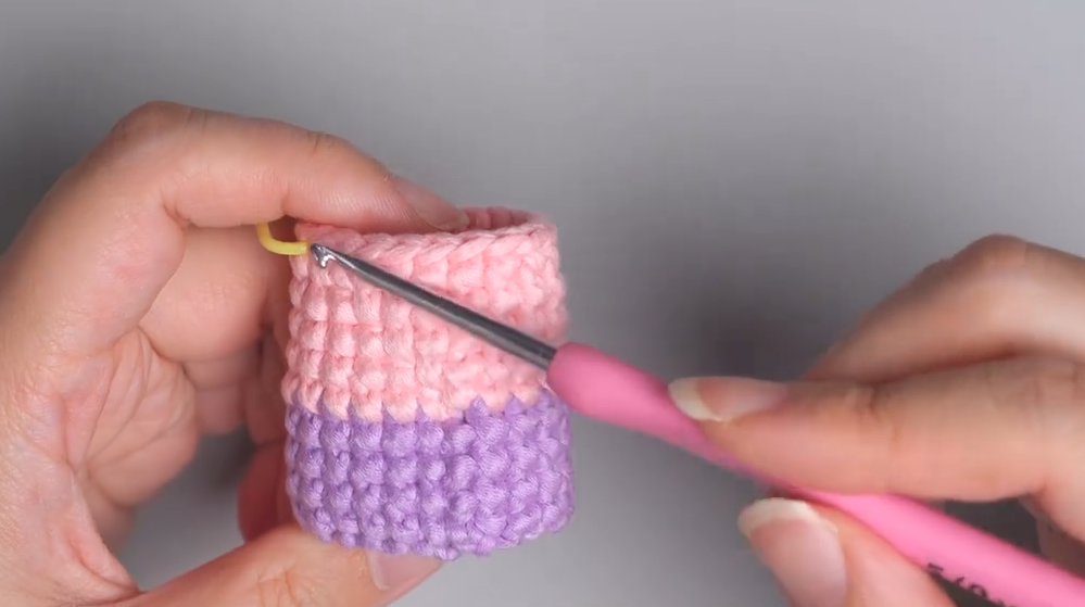 Crochet work in progress showing a clean vertical line where pink and purple colors meet