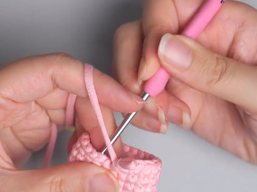 Close-up of the hook pulling a loop of yarn through for a jogless color change in crochet
